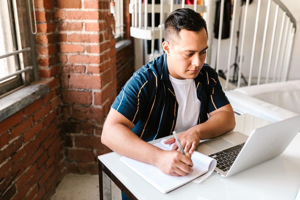 A student studying with a laptop and notebook