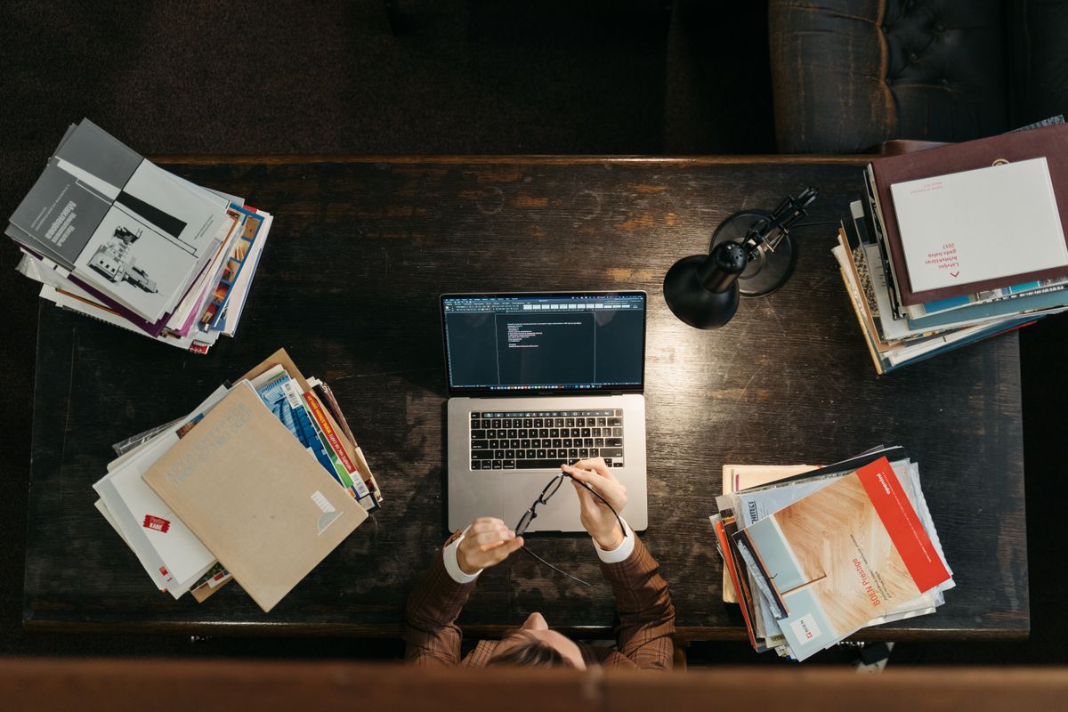 Study desk with stacks of books, a laptop, and a lamp